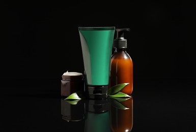 Photo of Facial cream and other men's cosmetic products on black background