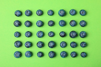 Photo of Tasty ripe blueberries on green background, flat lay