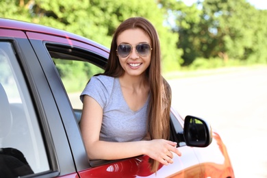 Happy beautiful young woman in car