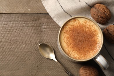 Photo of Delicious eggnog with cinnamon and walnuts on wooden table, flat lay. Space for text