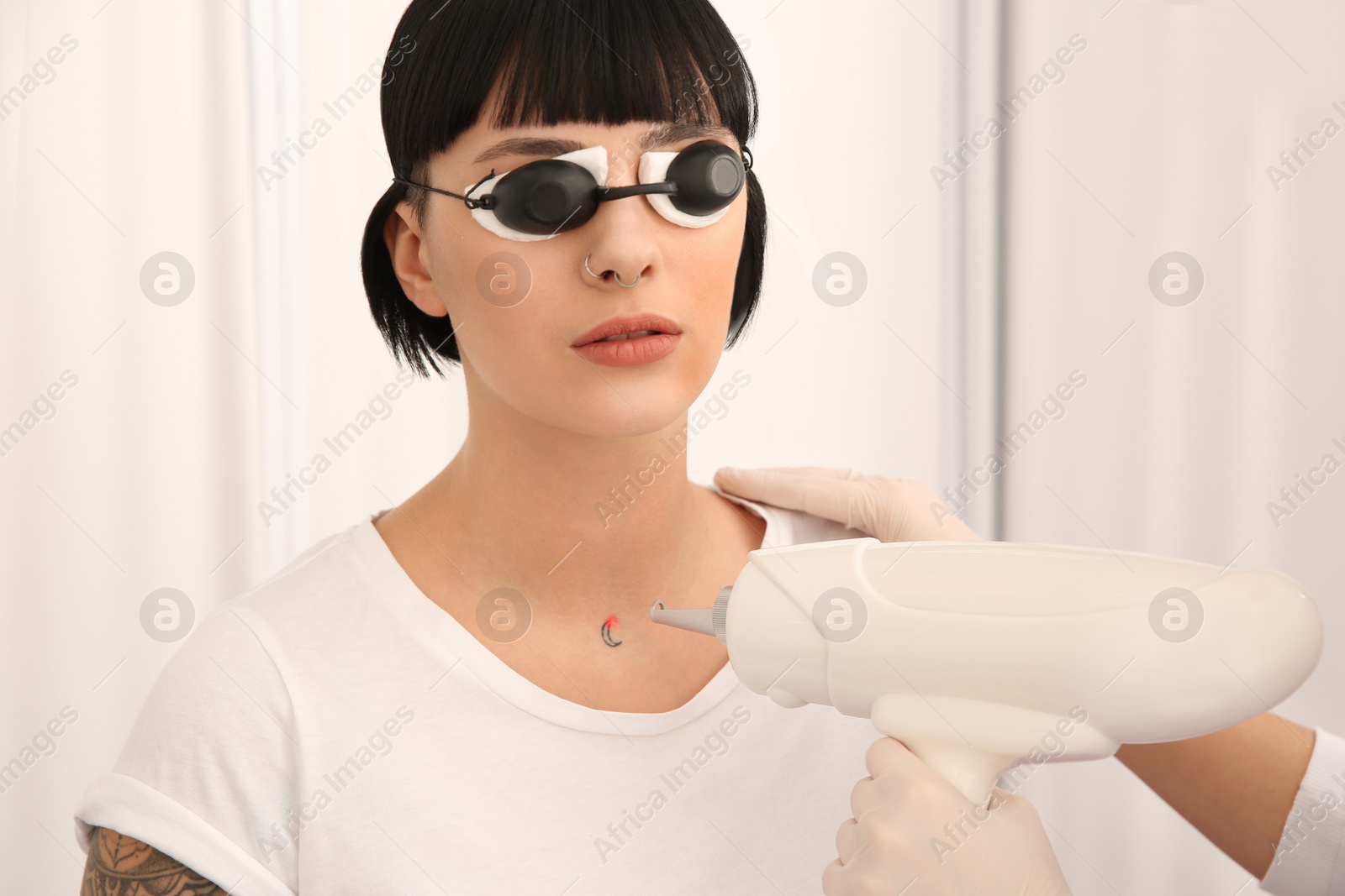 Photo of Young woman undergoing laser tattoo removal procedure in salon, closeup