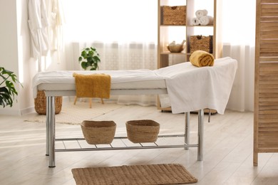 Photo of Comfortable massage table with clean towels in spa center