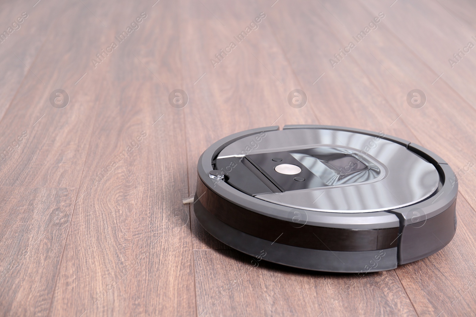 Photo of Hoovering floor with modern robotic vacuum cleaner indoors