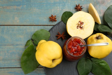 Delicious quince jam and fruits on light blue wooden table, flat lay