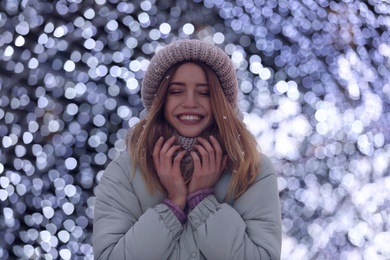 Photo of Happy young woman near festive lights in evening. Christmas celebration