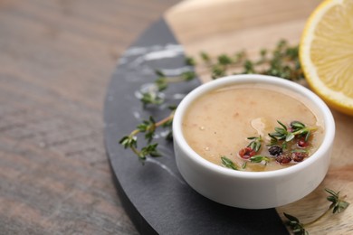 Photo of Delicious turkey gravy, thyme and peppercorns on wooden table, closeup. Space for text
