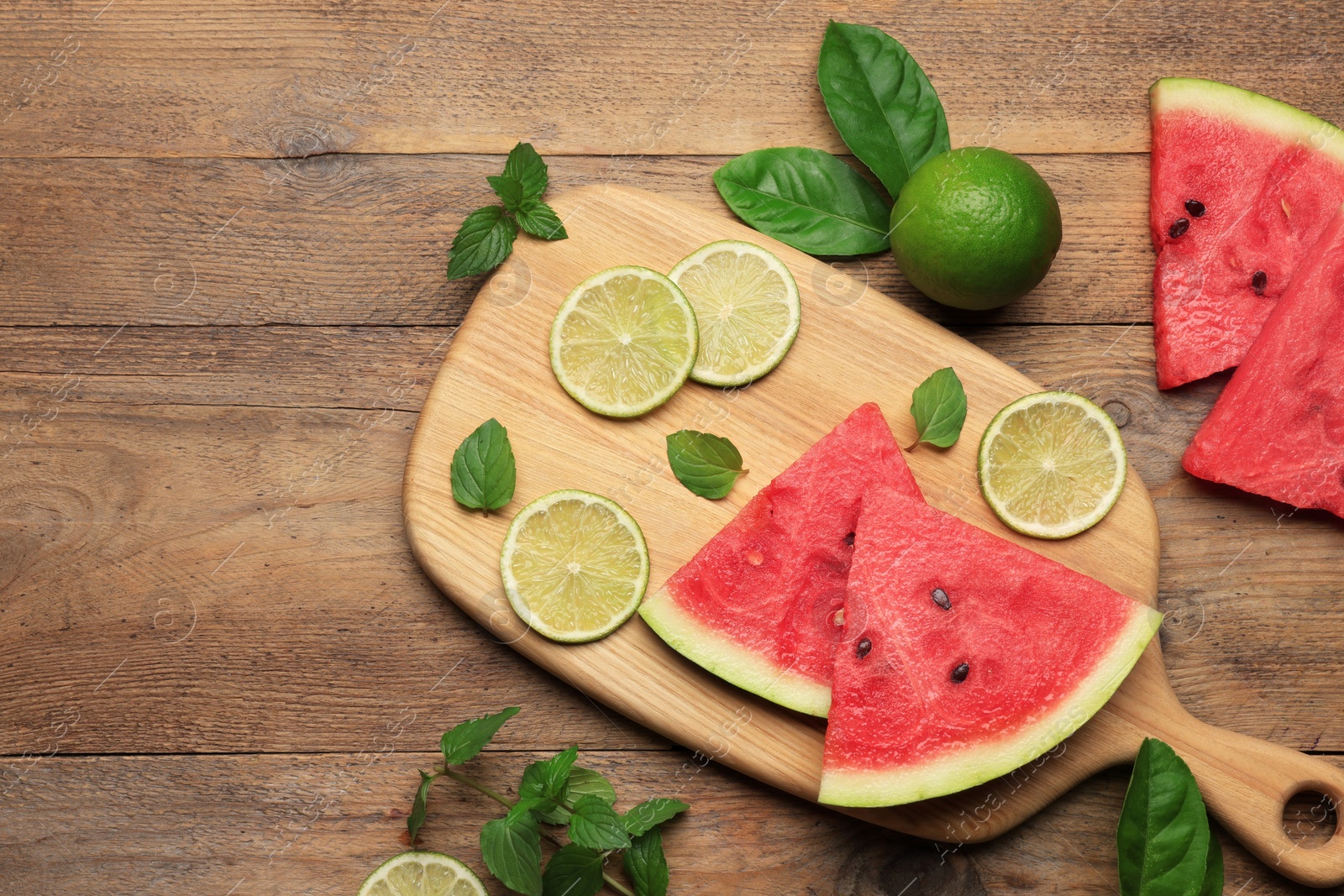 Photo of Tasty sliced watermelon and limes on wooden table, flat lay