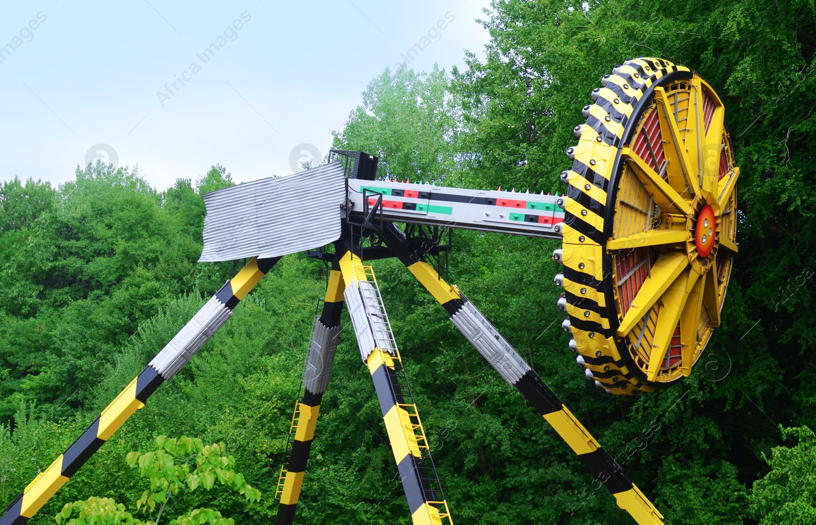 Photo of Large colorful Tomahawk attraction and green trees in amusement park