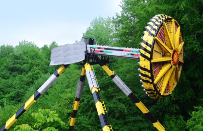 Large colorful Tomahawk attraction and green trees in amusement park
