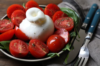 Delicious burrata cheese with tomatoes and basil served on wooden table, closeup