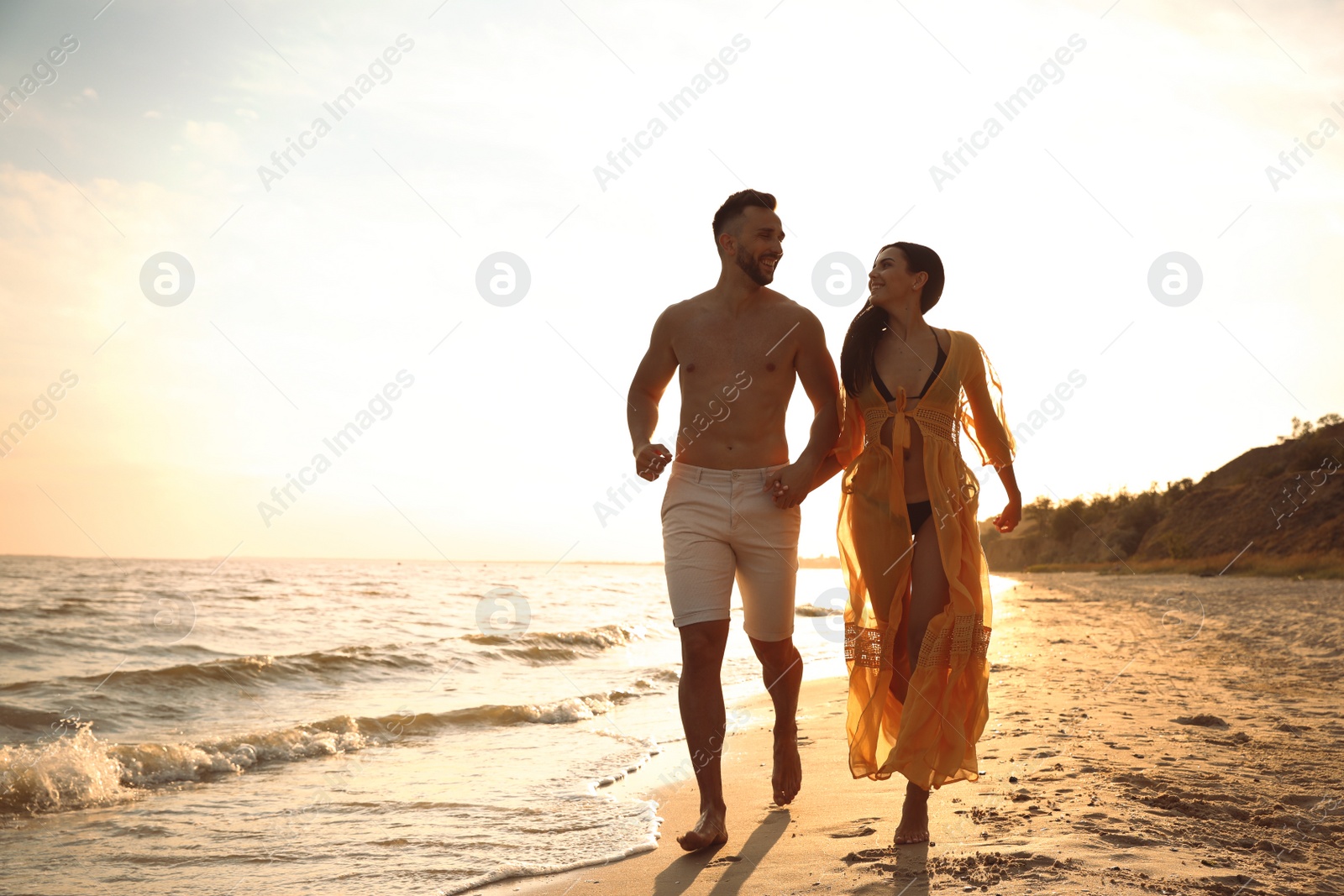 Photo of Happy young couple running together on beach at sunset