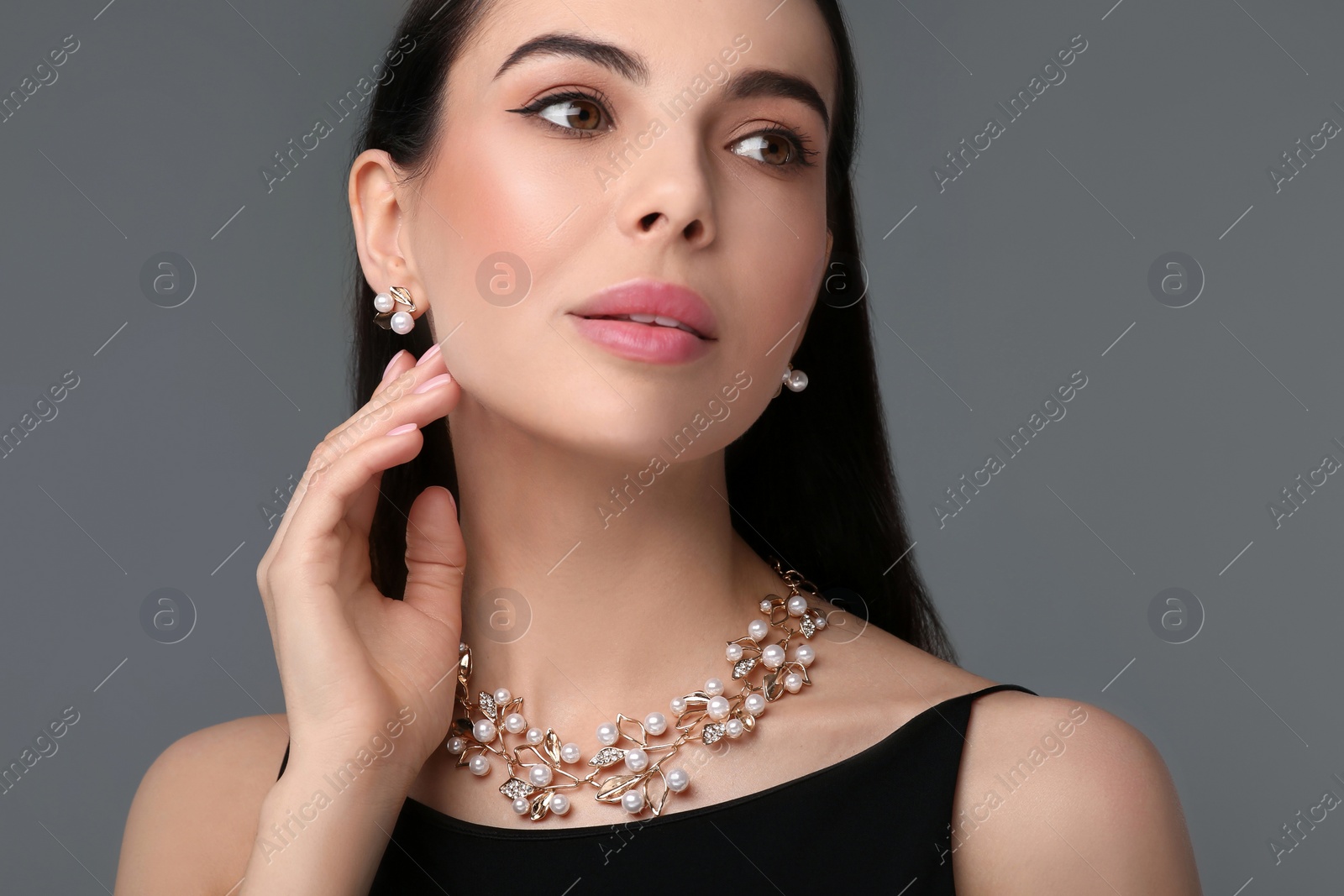 Photo of Beautiful young woman with elegant jewelry on dark grey background