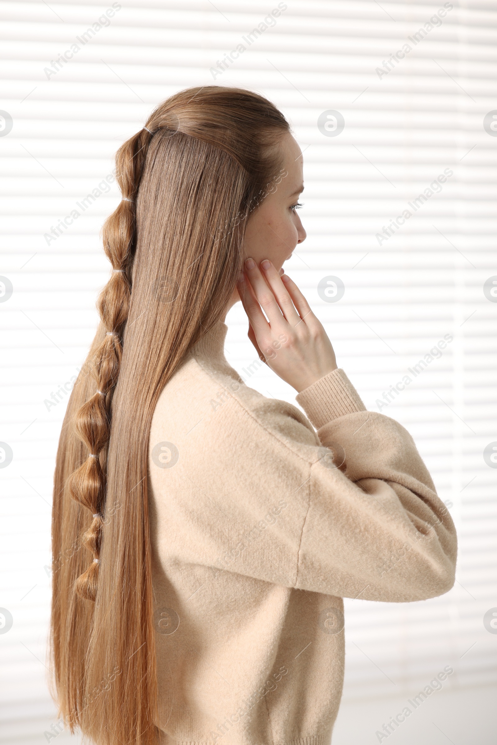 Photo of Young woman with long braided hair indoors