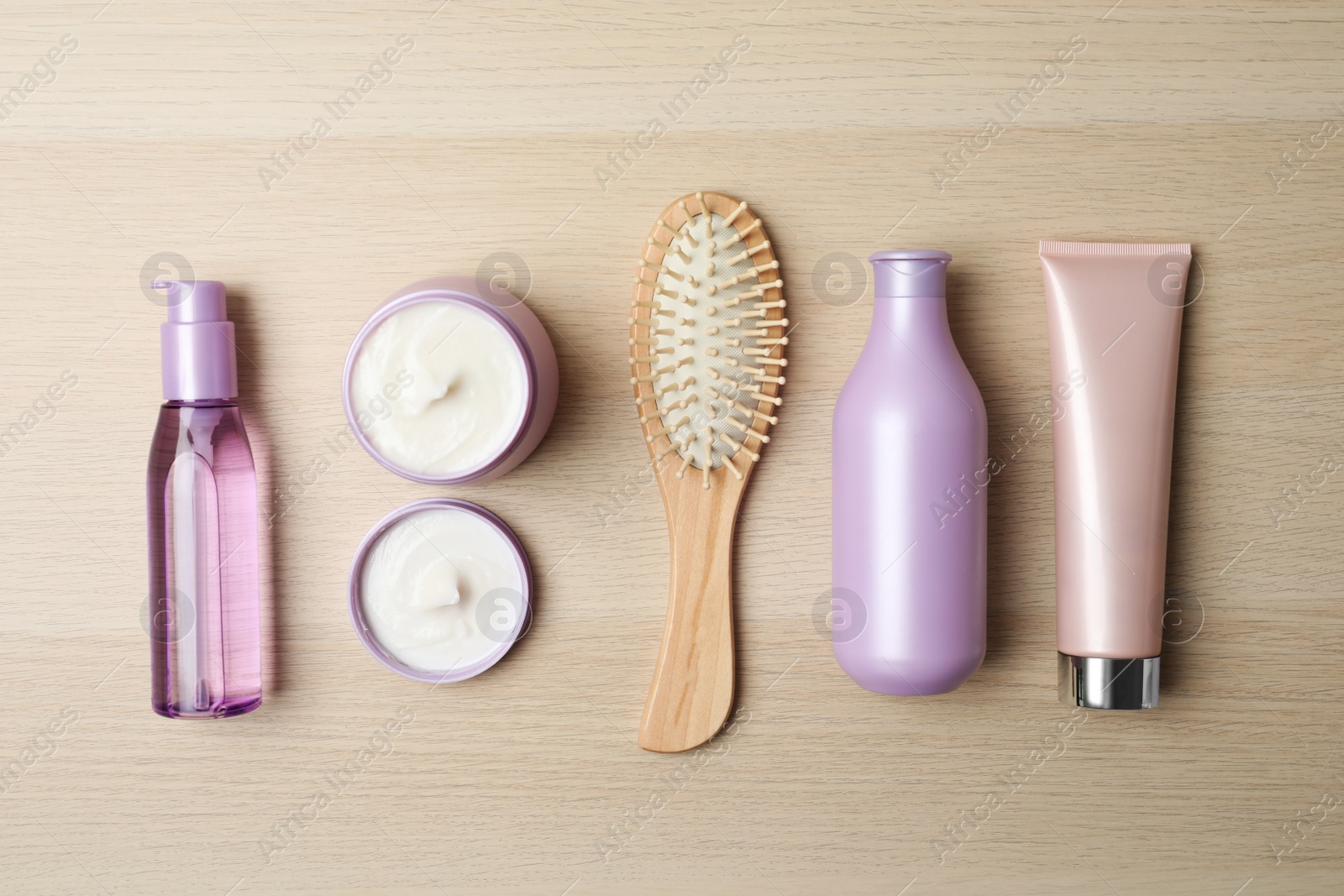 Photo of Different hair care products and brush on wooden table, flat lay