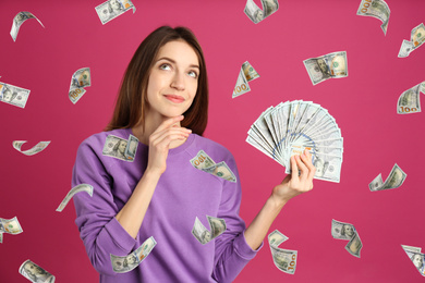 Woman with American dollars under money rain on color background