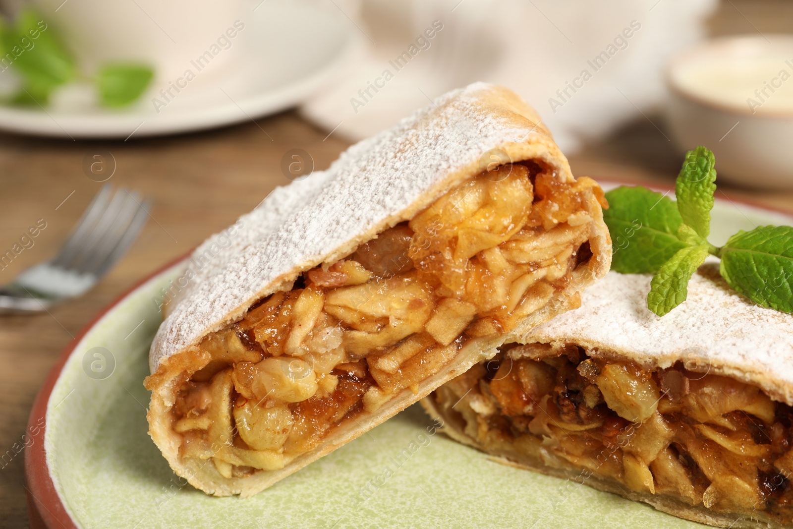 Photo of Delicious strudel with apples, nuts and raisins on plate, closeup