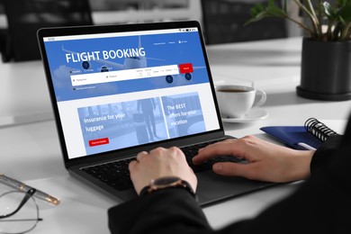 Image of Woman using laptop to book flight at white table, closeup
