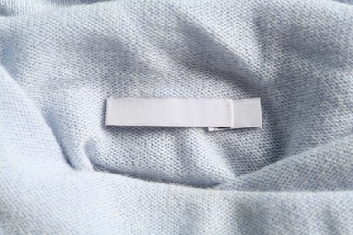 Photo of Blank clothing label on stylish cashmere apparel, closeup
