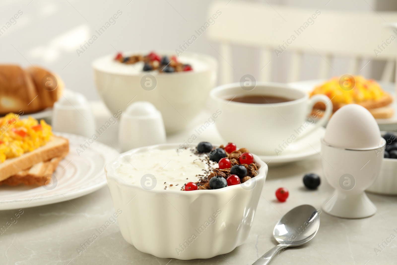 Photo of Delicious breakfast with yogurt, granola and berries served on light table