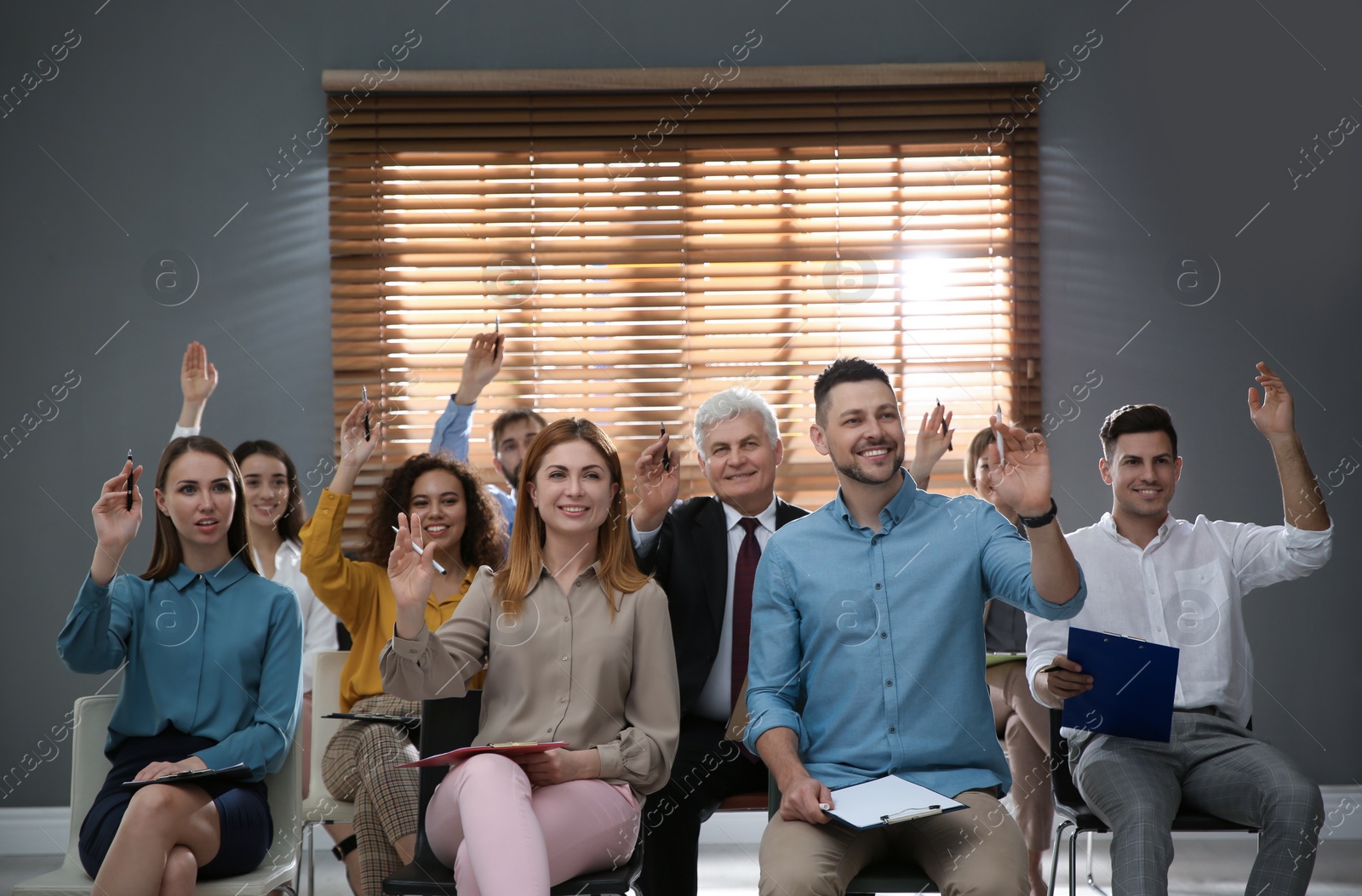 Photo of People raising hands to ask questions at seminar in office