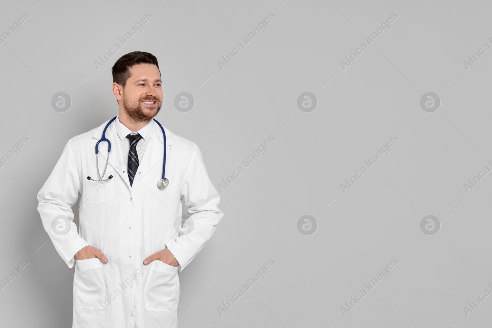 Photo of Portrait of smiling doctor on light grey background, space for text