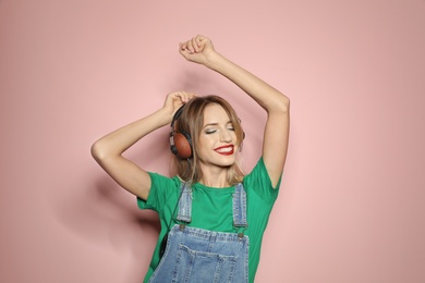 Beautiful young woman with healthy long blonde hair and headphones on color background