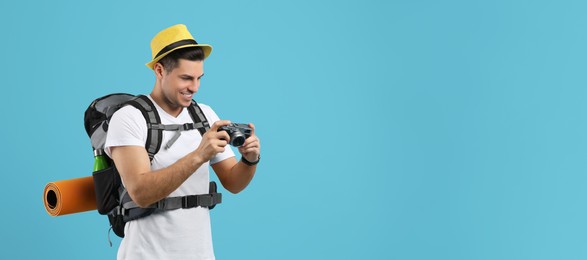 Photo of Male tourist with travel backpack and camera on turquoise background