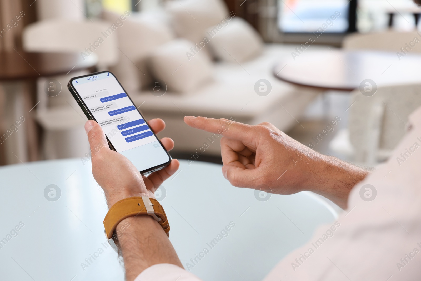 Image of Man texting via mobile phone indoors, closeup. Device screen with messages