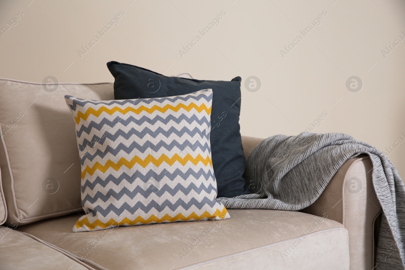 Photo of Cozy sofa with pillows and plaid near light wall. Idea for living room interior design