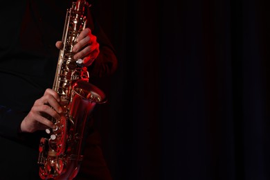Photo of Man with saxophone on dark background, closeup. Space for text