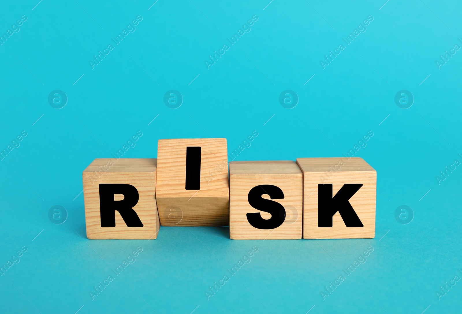 Photo of Word Risk made of wooden cubes on turquoise background