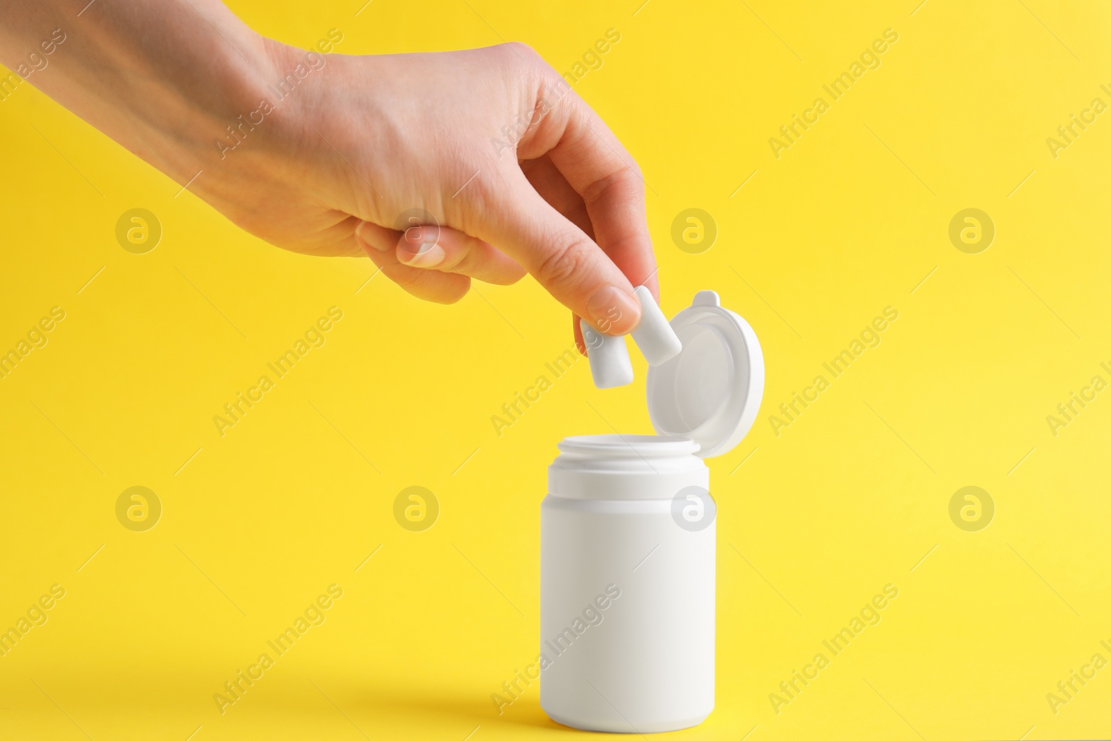 Photo of Woman taking chewing gums from jar on yellow background, closeup