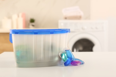 Laundry container and washing detergent capsules on table indoors