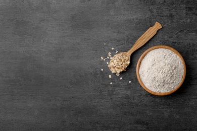 Bowl with oat flour and flakes in spoon on gray background