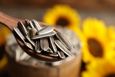 Photo of Wooden spoon with raw sunflower seeds, closeup. Space for text