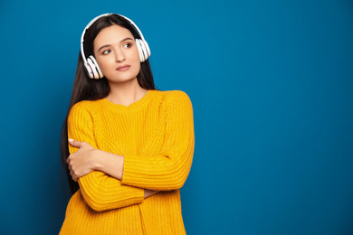 Photo of Young woman listening to audiobook on blue background. Space for text