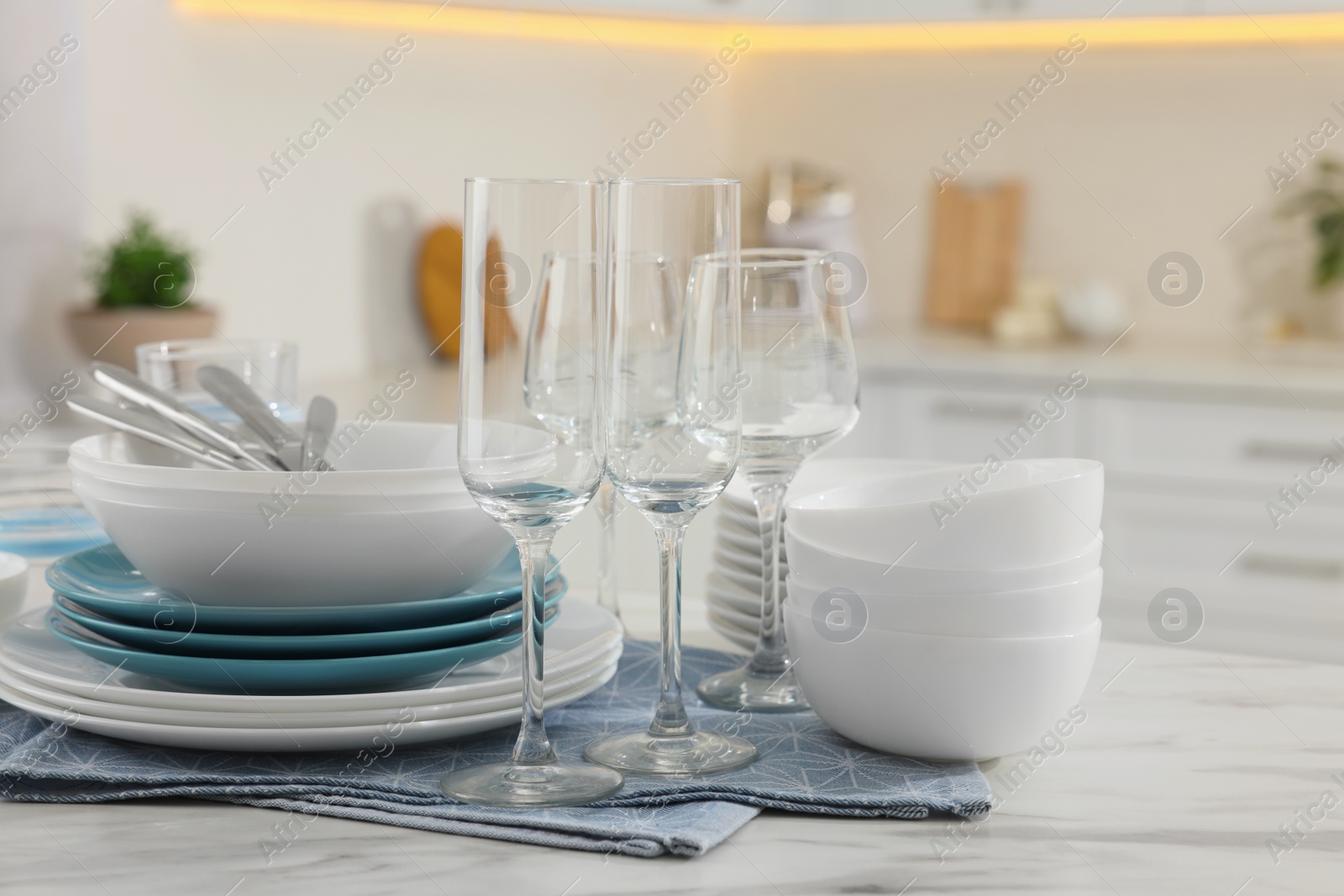 Photo of Different clean dishware, cutlery and glasses on white table in kitchen