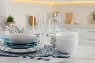 Photo of Different clean dishware, cutlery and glasses on white table in kitchen