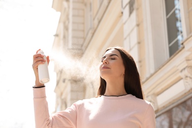 Young woman applying thermal water on face outdoors. Cosmetic product