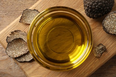 Photo of Glass bowl of truffle oil with wooden board on table, top view