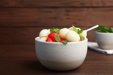 Bowl with melon and watermelon balls on wooden table