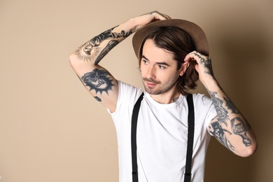 Photo of Young man with tattoos on arms against beige background