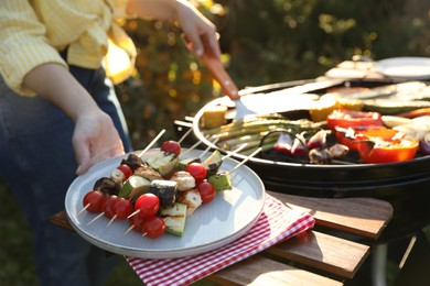 Photo of Woman cooking vegetables on barbecue grill outdoors, closeup