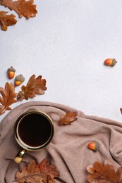 Flat lay composition with cup of hot drink and autumn leaves on light grey textured table. Space for text