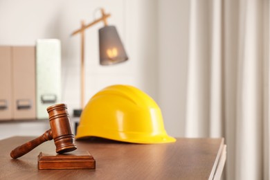 Law concept. Gavel and yellow hard hat on wooden table, space for text