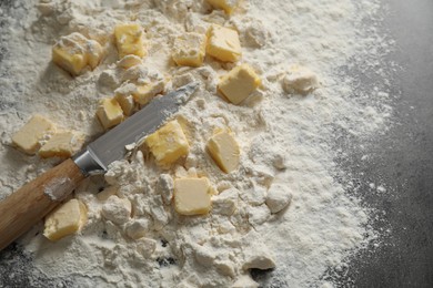 Photo of Making shortcrust pastry. Flour, butter and knife on grey table, top view