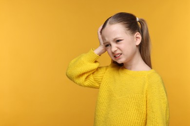 Little girl suffering from headache on yellow background. Space for text