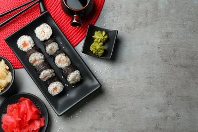 Photo of Tasty sushi rolls served on grey table, flat lay. Space for text