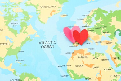 Photo of Honeymoon concept. Two red paper hearts on world map, top view