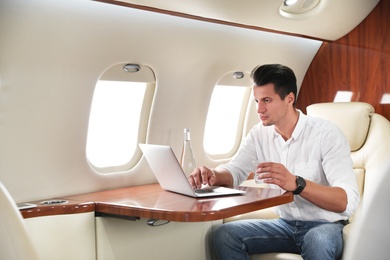 Image of Handsome man working with laptop on plane. Comfortable flight